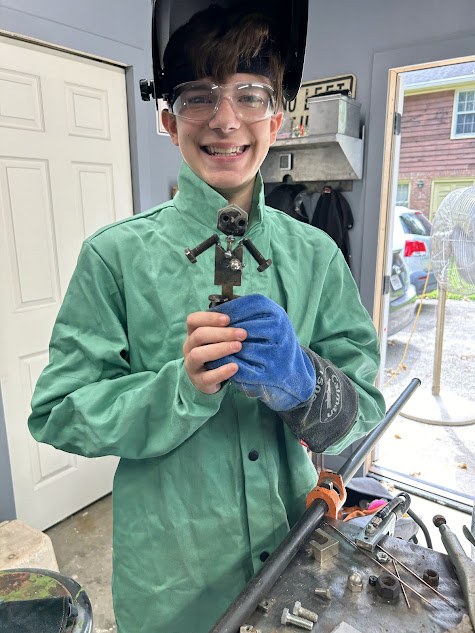 Young student showing off welded metal robot figure